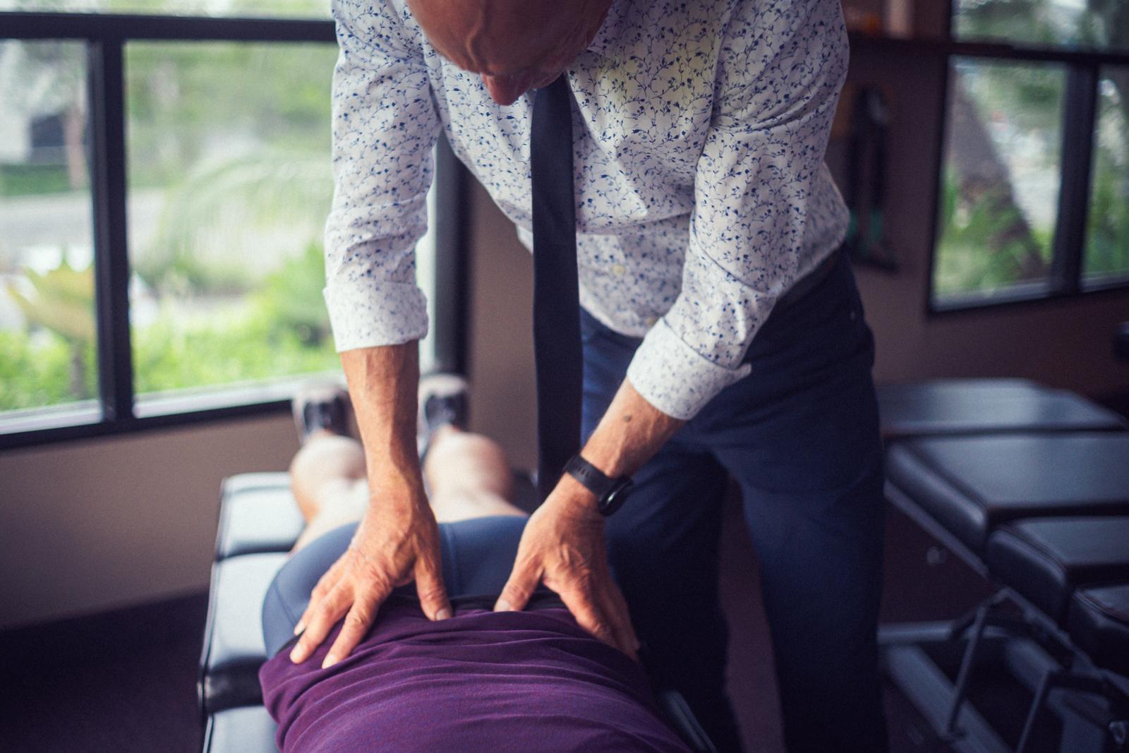 Dr. Billy DeMoss adjusting a patient's back at DeMoss Chiropractic, Newport Beach