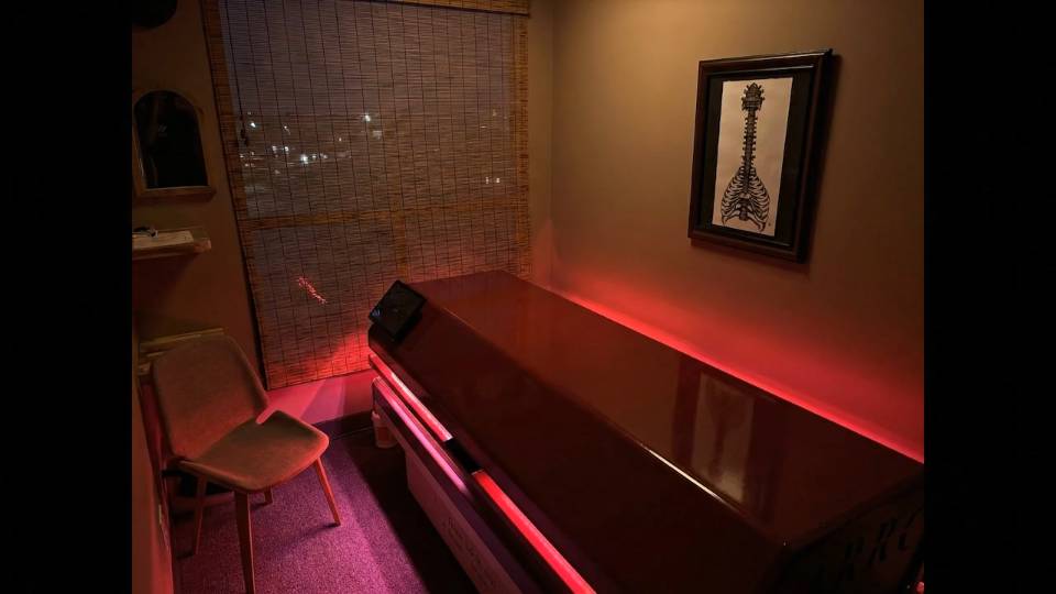 The full-body LED light bed in a treatment room at DeMoss Chiropractic, lit deep red